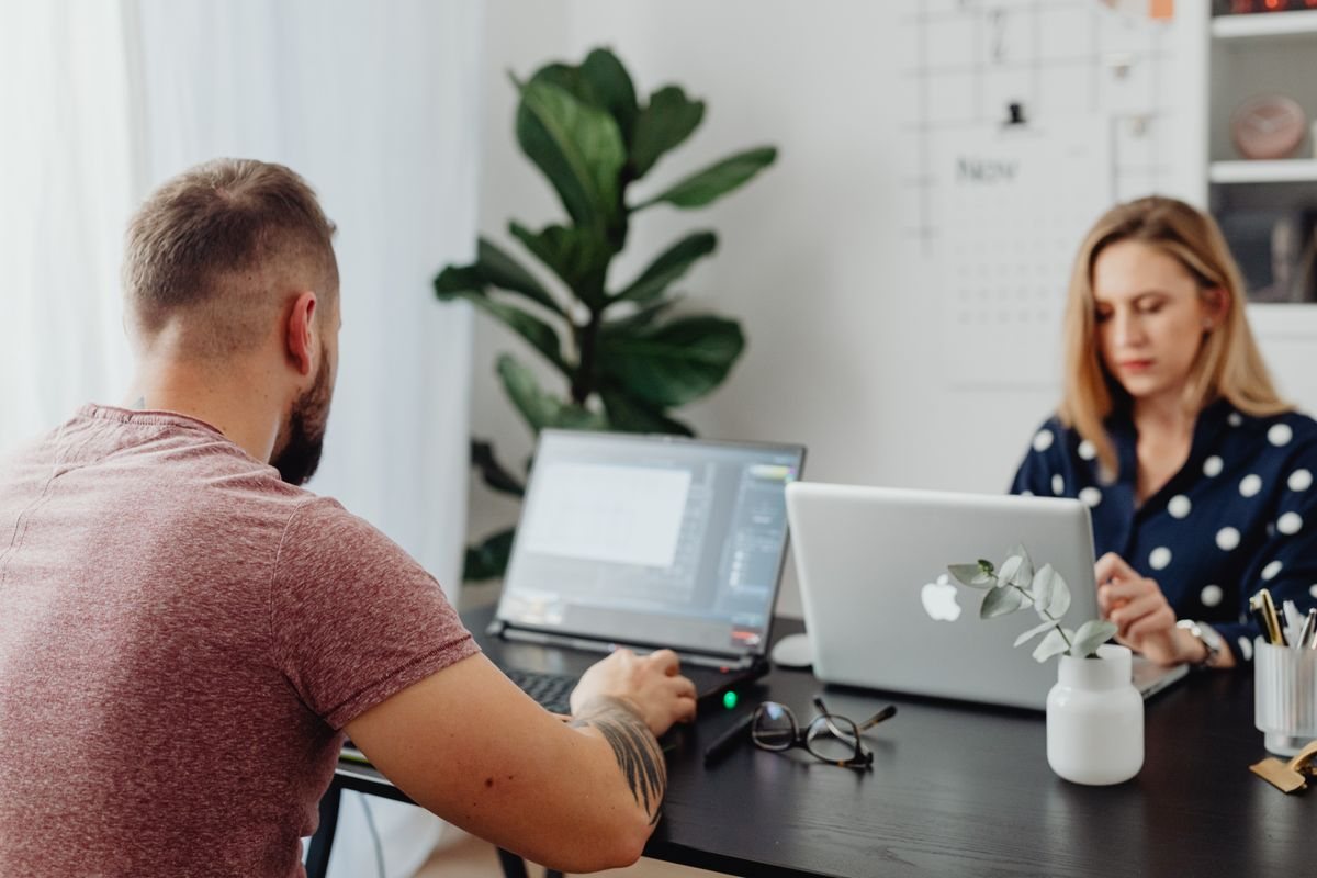 Two people working at a desk with laptops