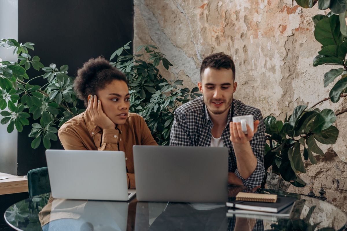 Two coworkers on laptops side by side